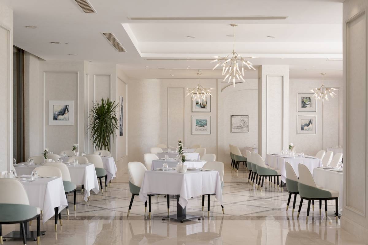 Innenansicht des Restaurants im Xanadu Makadi Bay Hotel mit gedeckten Tischen und eleganten Kronleuchtern.