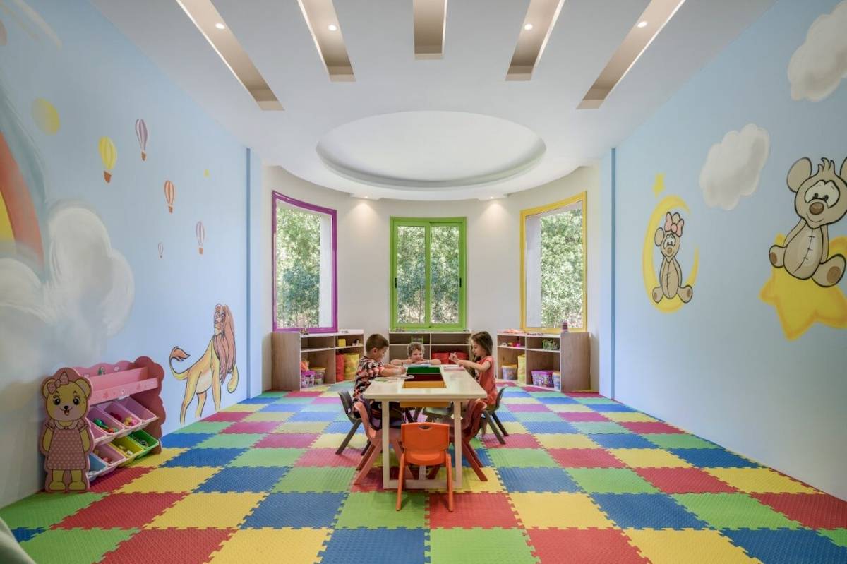 Kinderzimmer im Xanadu Makadi Bay Hotel mit bunten Bodenfliesen und gemalten Tieren an den Wänden.