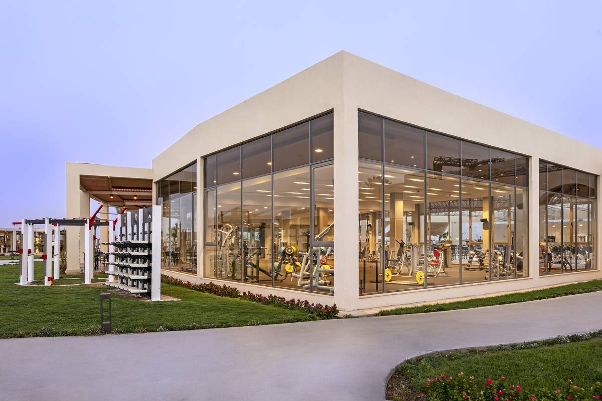 Außenansicht des Fitnesscenters im Xanadu Makadi Bay Hotel, das Fitnessgeräte und eine gepflegte Rasenfläche zeigt.