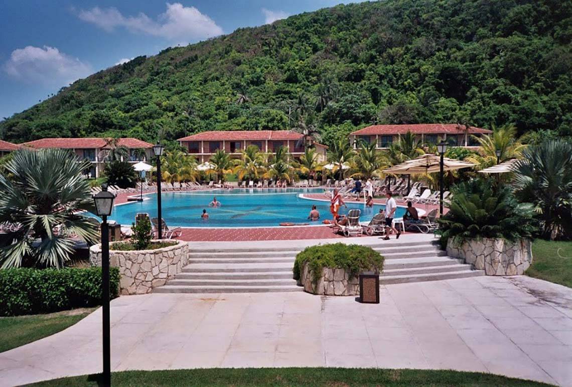 Außenbereich des Memories Jibacoa Resorts mit Swimmingpool und bergigem Hintergrund.