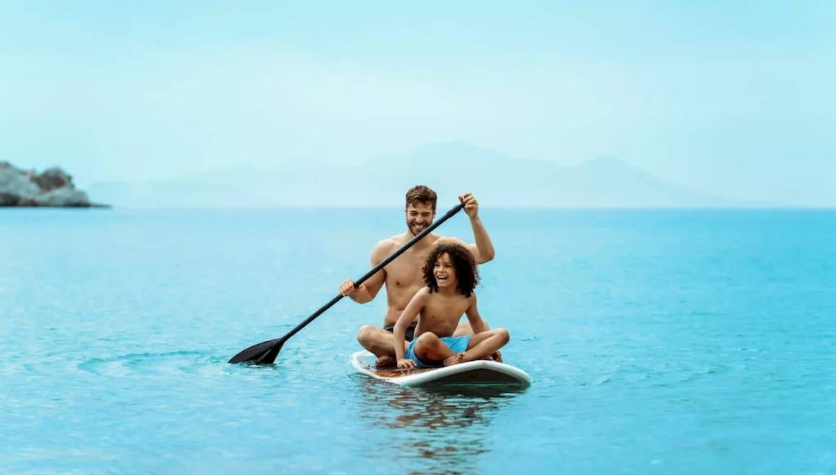 Ein Vater und sein Sohn paddeln auf einem SUP-Board im Meer.