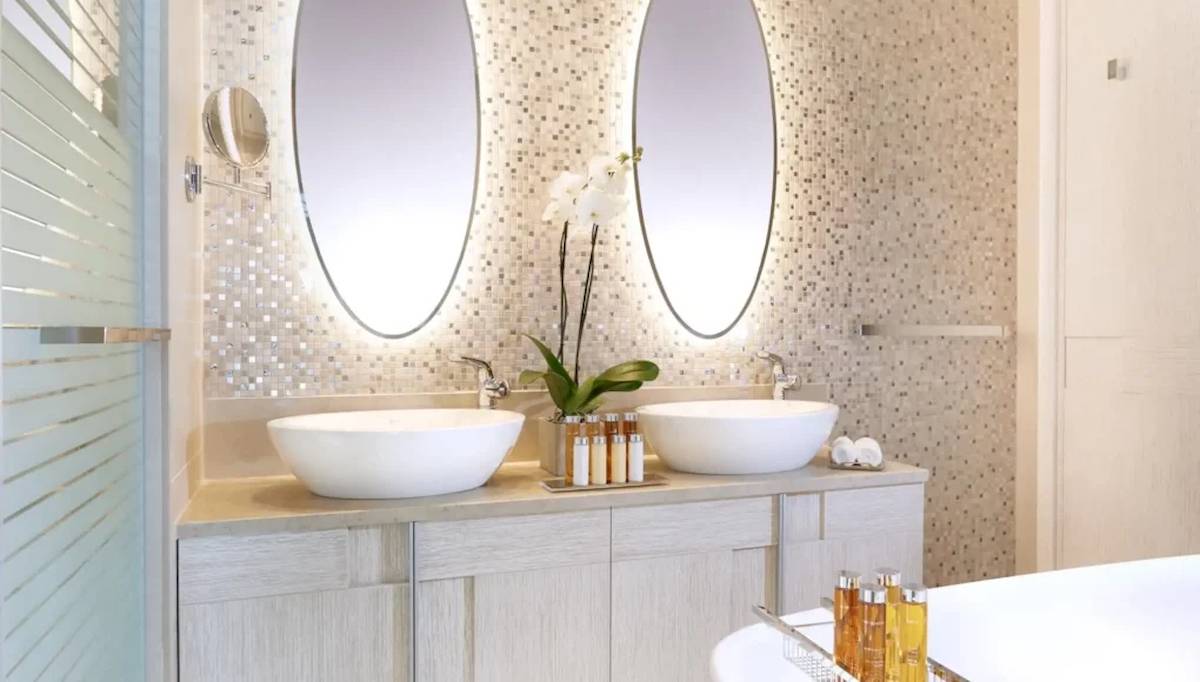 Badezimmer im Ikos Dassia Hotel mit zwei Waschbecken und Spiegeln.