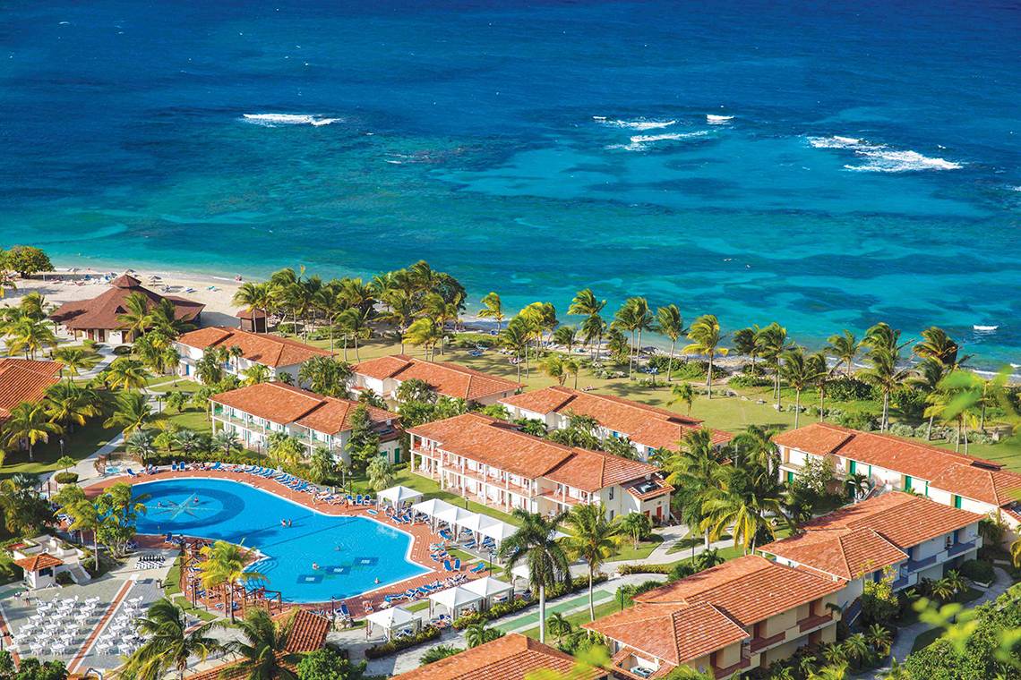 Oberflächenansicht des Memories Jibacoa Resorts mit Pool, Gebäuden und Meer im Hintergrund.