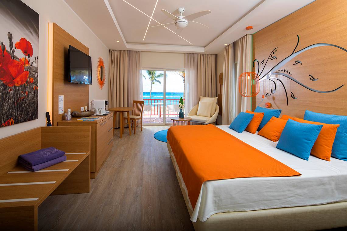 Ein modernes Hotelzimmer im Memories Jibacoa Resort mit einem großen Bett, einem Fernseher und einem Ausblick auf den Ozean.