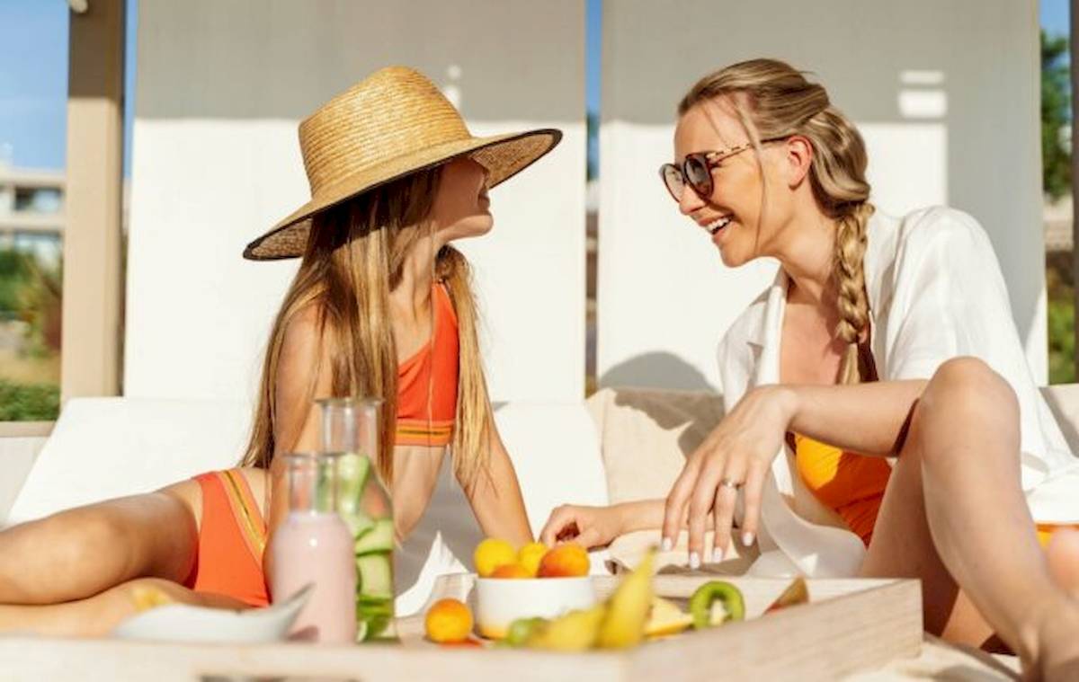 Zwei Frauen im Ikos Dassia Hotel sitzen am Tisch mit Früchten und Getränken.