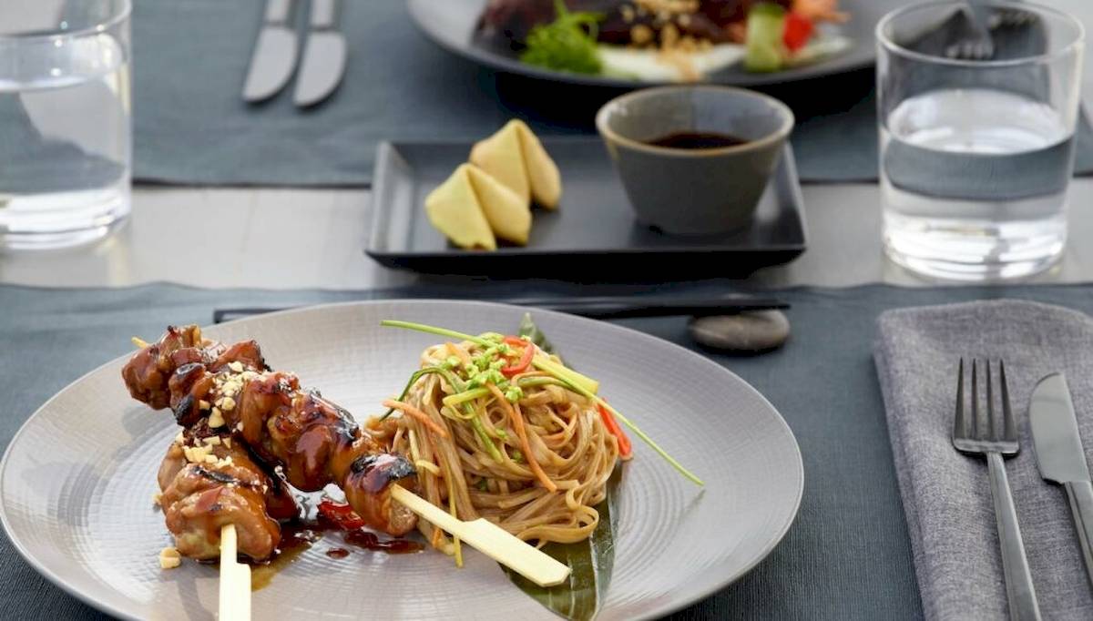 Ein Teller mit asiatischem Gericht im Hotel Ikos Odisia, bestehend aus gegrilltem Fleisch und Nudeln.