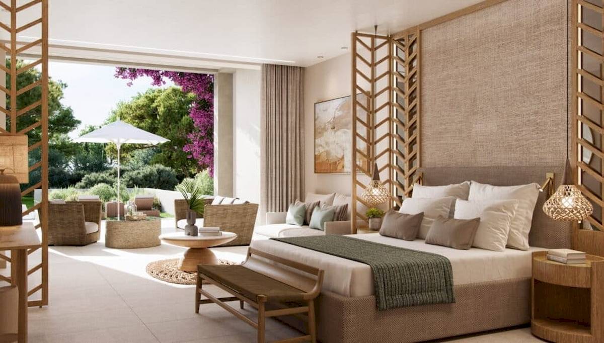 Innenansicht eines Zimmers im Ikos Odisia Hotel mit großem Bett, Sofas, Tisch und Pflanzen.