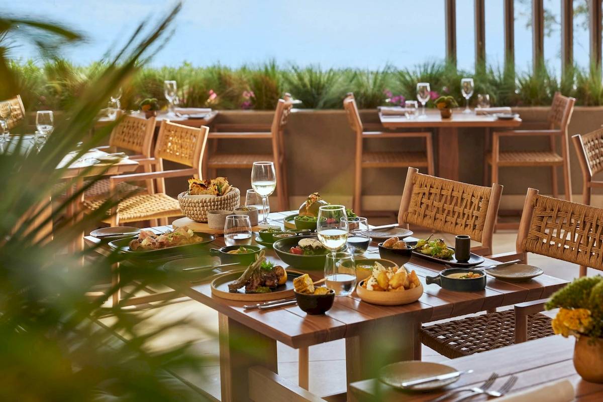Außenbereich des Speisesaals im Ikos Odisia Hotel mit gedeckten Tischen und Blick auf eine Terrasse.