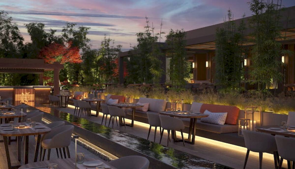 Außenbereich des Ikos Olivia Hotels mit beleuchteten Tischen und Bänken