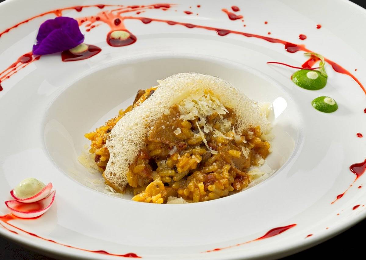 Ein Gericht in einem weißen Teller mit roter Sauce und grünen Beilagen.