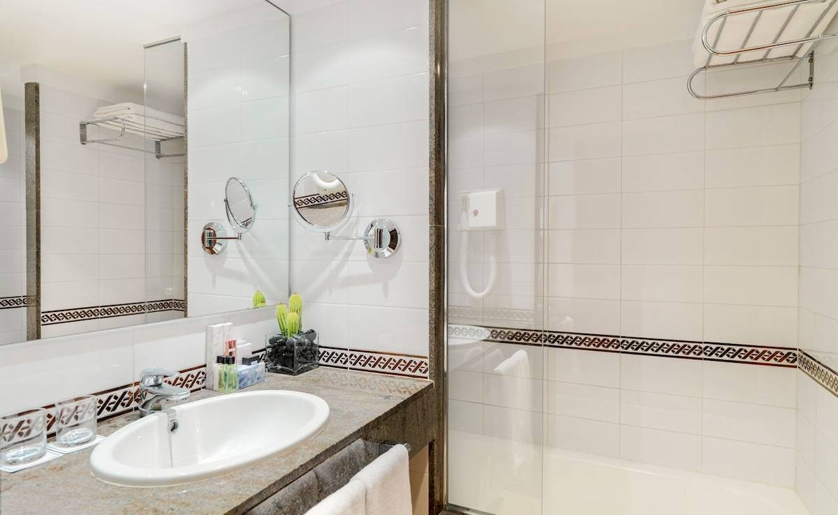 Badezimmer im H10 Blue Mar Boutique Hotel mit Waschbecken, Spiegel und Dusche.