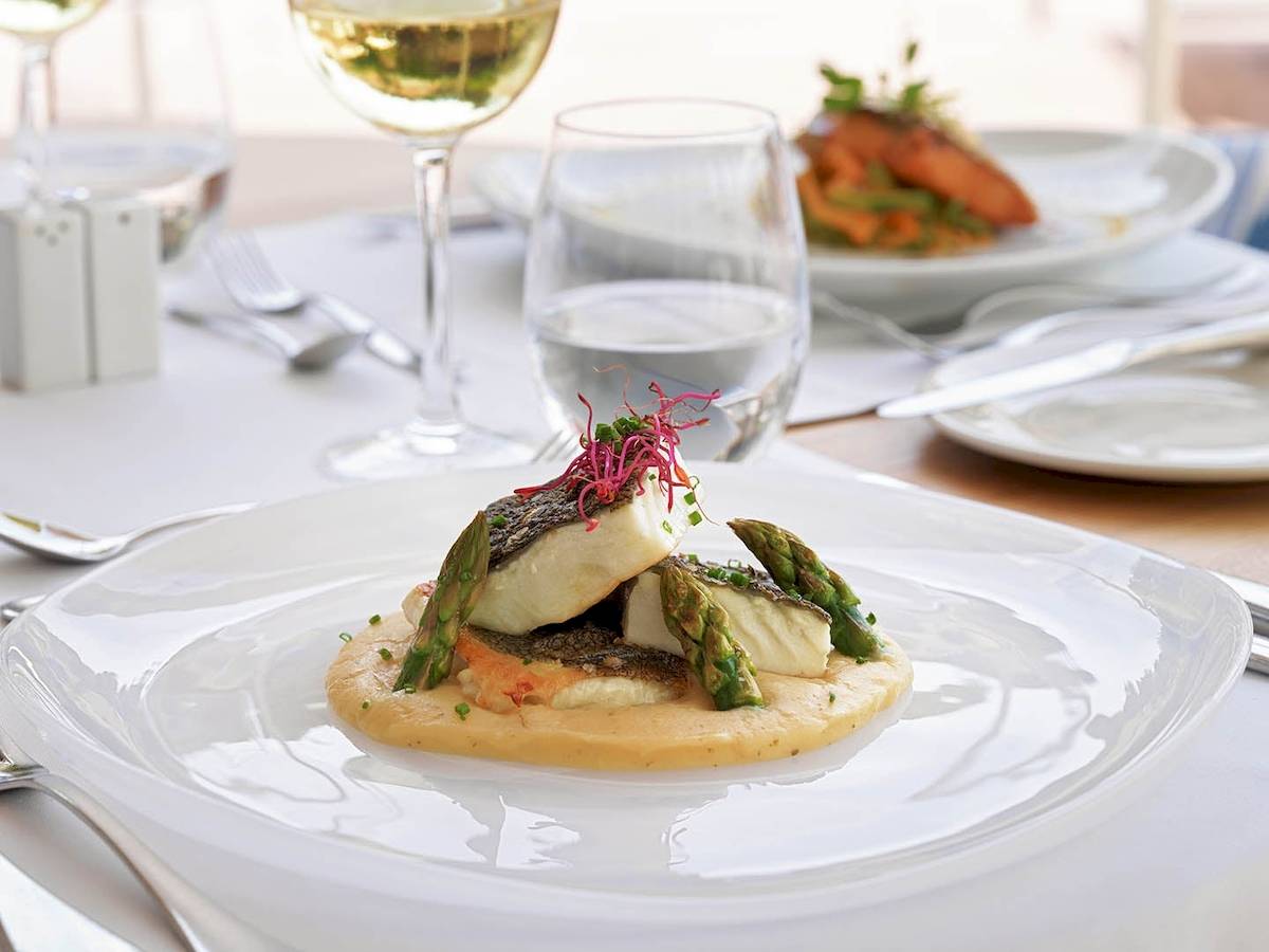 Fischgericht auf einem weißen Teller im H10 Blue Mar Boutique Hotel Restaurant