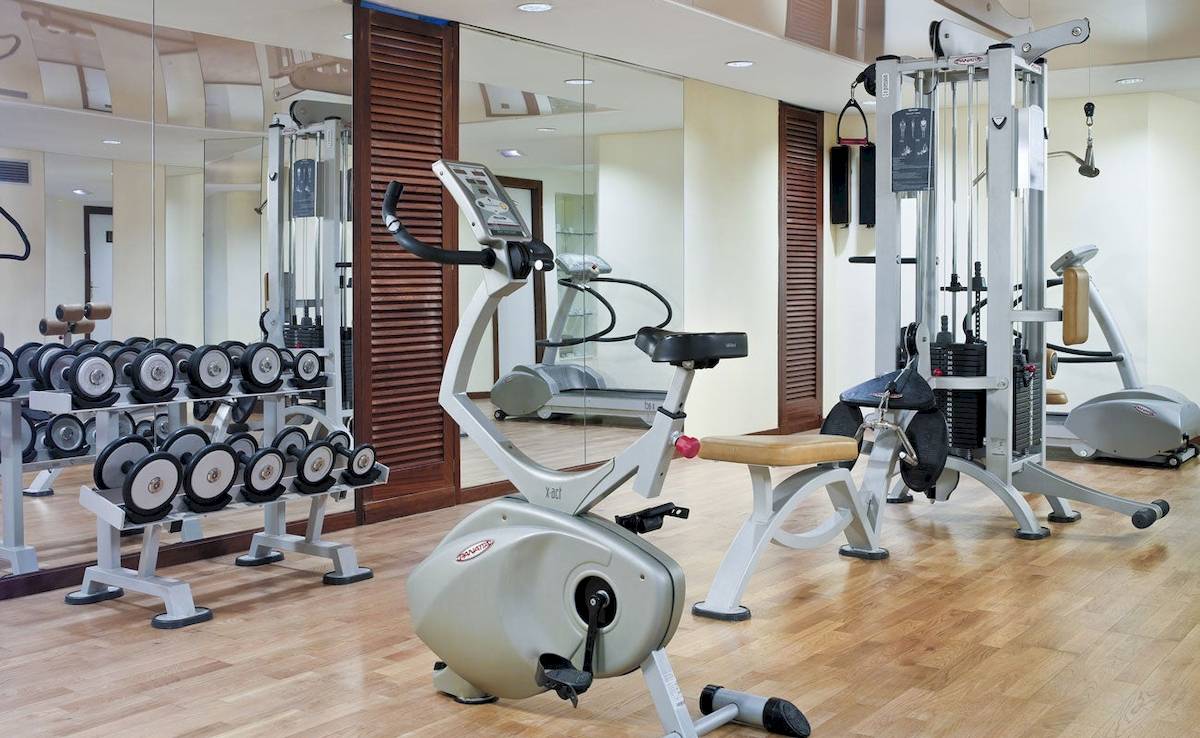 Fitnessraum des H10 Blue Mar Boutique Hotels mit Geräten und Spiegeln.