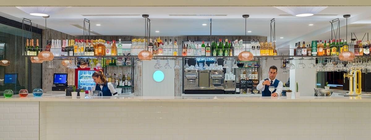 Die Bar Theta im H10 Casa del Mar Hotel mit gut gekleideten Barkeepern und einer Auswahl an Getränken.