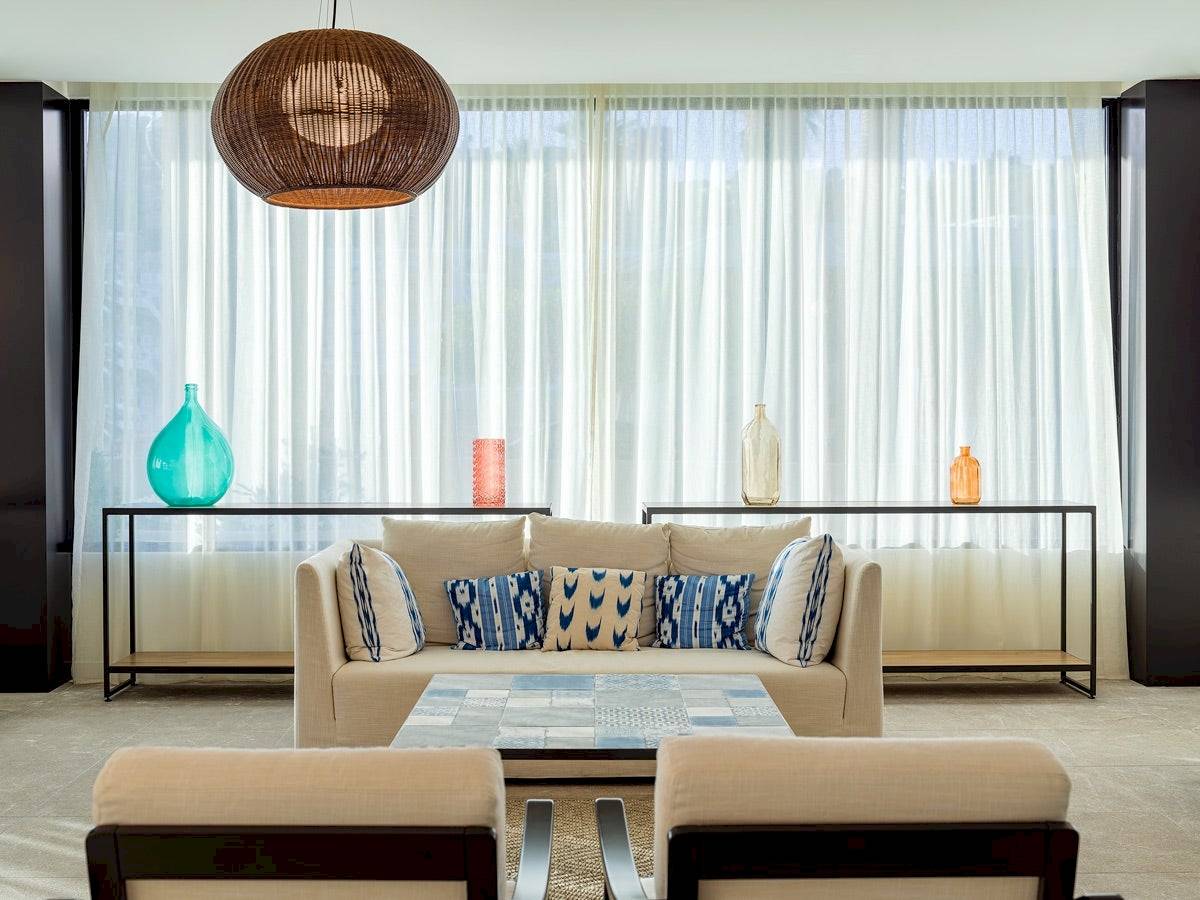 Wohnzimmer im H10 Casa del Mar Hotel mit Couch, Tisch und Dekorationsgegenständen.