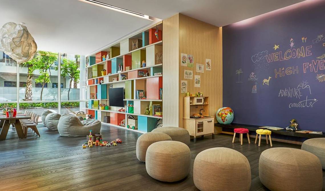 Kinderzimmer im FIVE Palm Jumeirah mit bunten Regalen, Spielsachen, Sofas und einer Wand mit Zeichnungen.