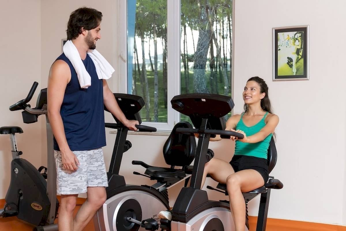 Mann und Frau trainieren im Fitnessstudio des Monachus Family Resorts auf Fahrrädern.