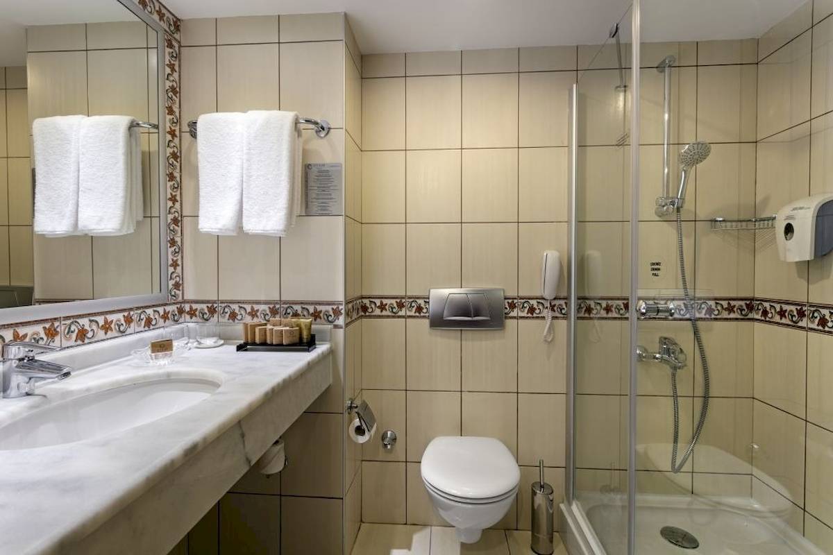 Badezimmer im Seven Seas Hotel Life mit Marmorwaschtisch, Spiegel, Handtüchern, Dusche und Toilette.