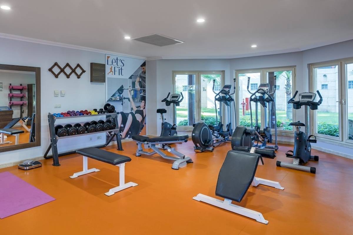 Fitnessraum im Seven Seas Hotel Life mit verschiedenen Trainingsgeräten und einer Person, die Hanteln benutzt.