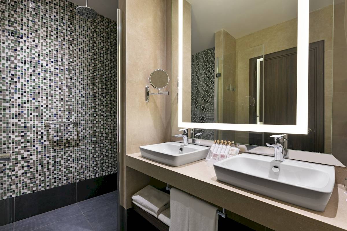 Badezimmer im Seven Seas Hotel Life mit zwei Waschbecken, Spiegel und Kacheln.