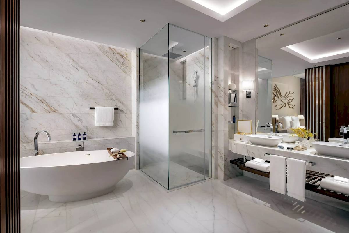 Badezimmer im Atlantis The Royal mit Badewanne, Glasdusche und Waschbecken.