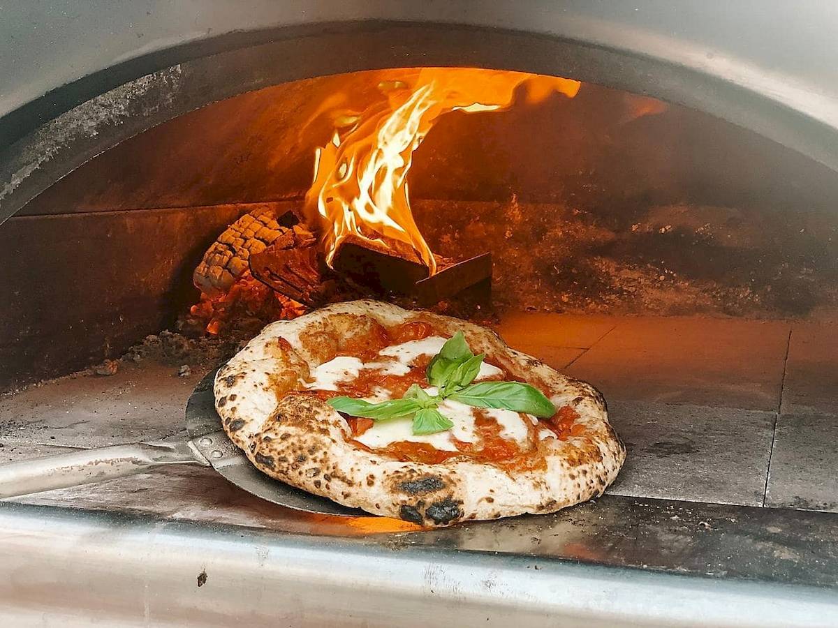 Pizza mit Mozzarella und Basilikum wird aus einem Ofen entnommen