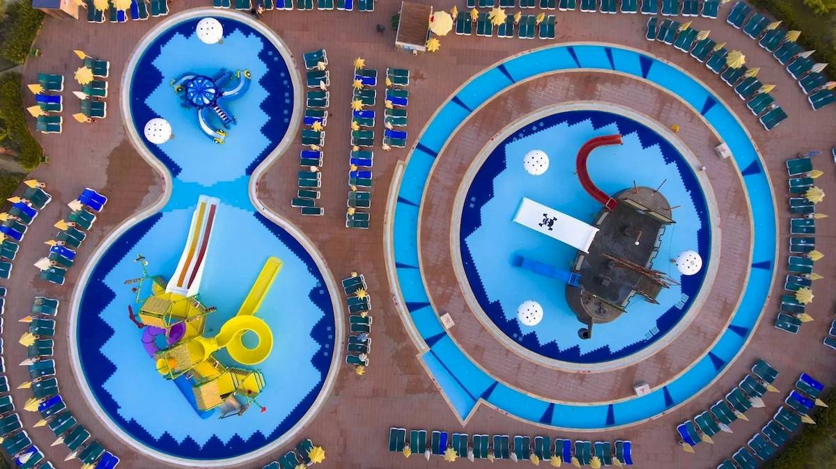 Luftaufnahme des Schwimmbads des Eftalia Ocean Hotels mit Wasserrutschen und Liegestühlen.