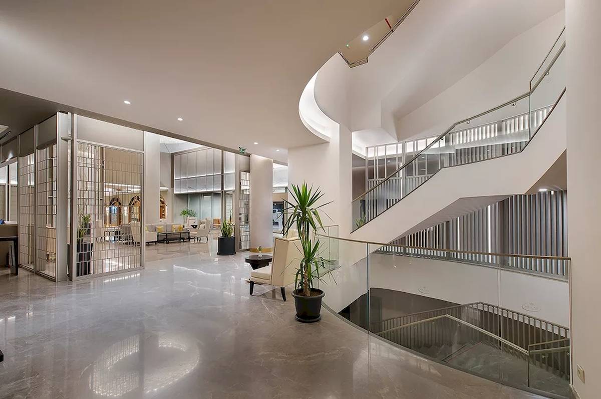 Innenbereich der Lobby des Melas Resorts mit Aufzug, Pflanzen und modernen Möbeln.