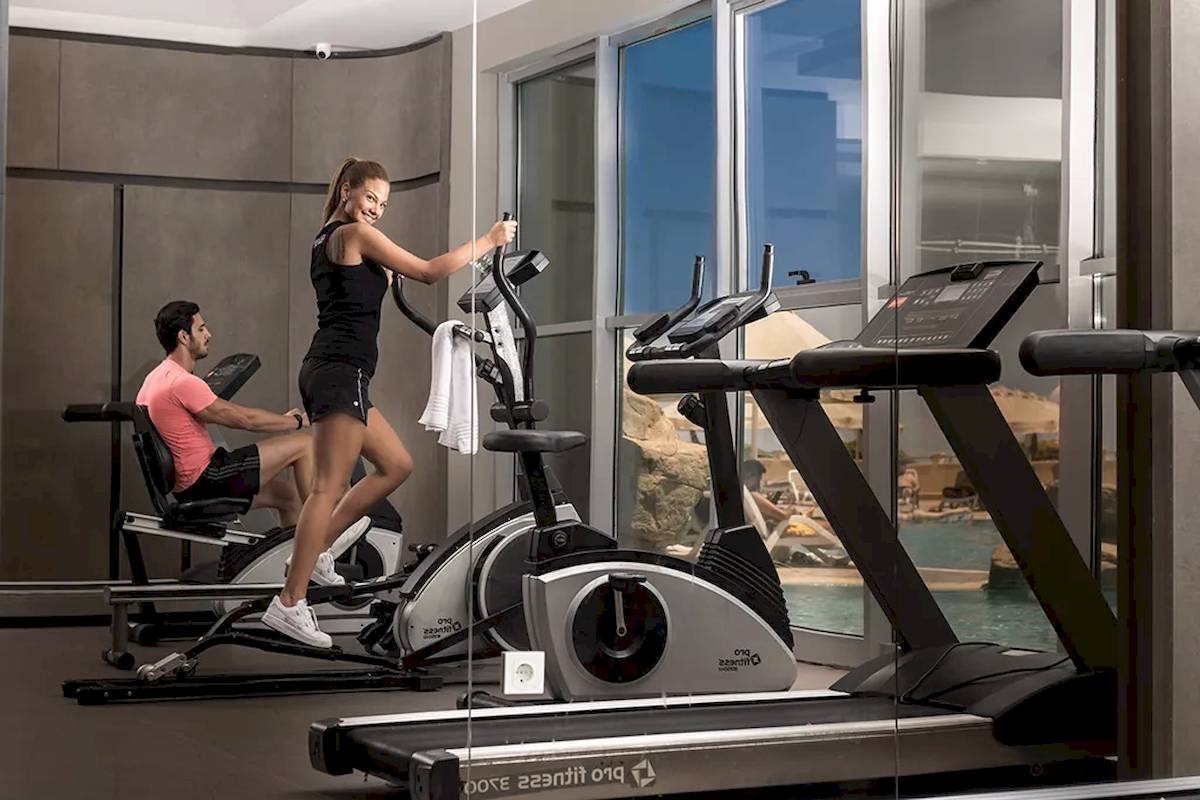 Fitnesscenter im Melas Resort mit Läuferin und Läufer auf Trainingsgeräten
