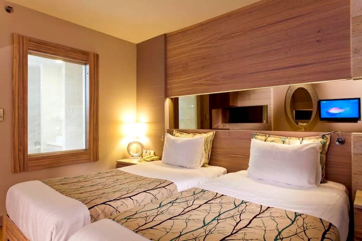 Doppelzimmer im Melas Resort mit zwei Betten, Fernseher und Holzwand