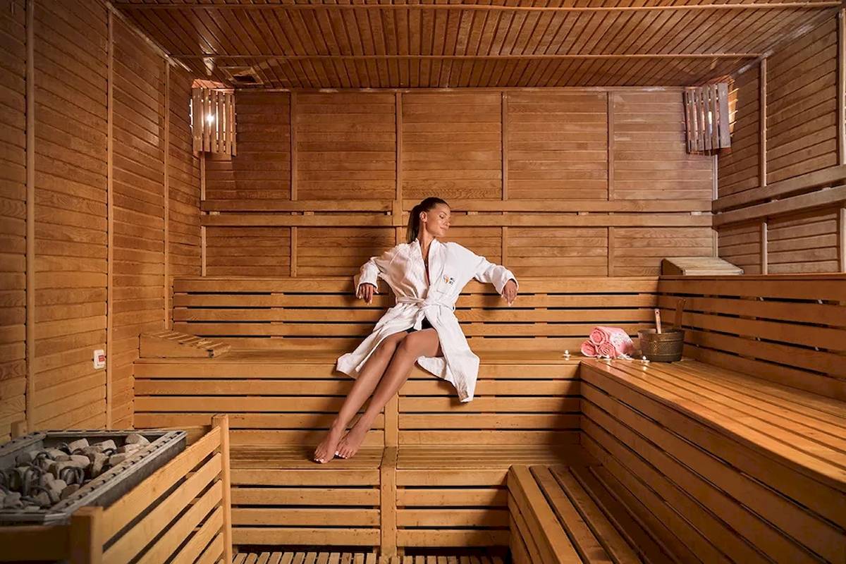 Frau sitzt in einem Holzsaunaraum des Melas Resorts