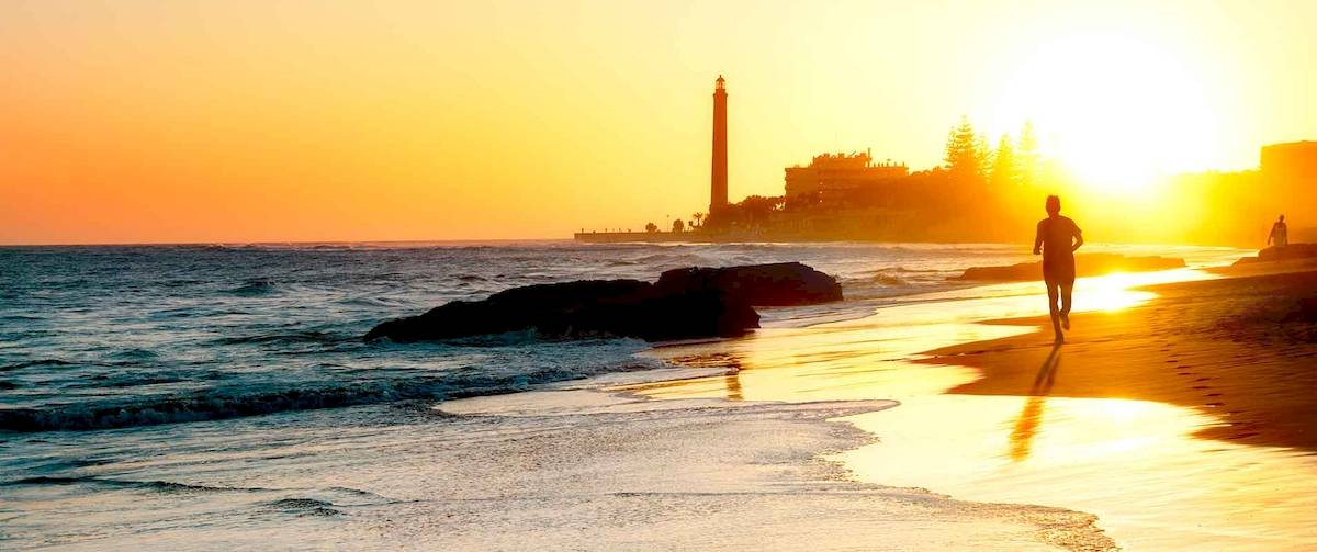 Person läuft auf dem Strand neben dem Europalace Hotel bei Sonnenuntergang