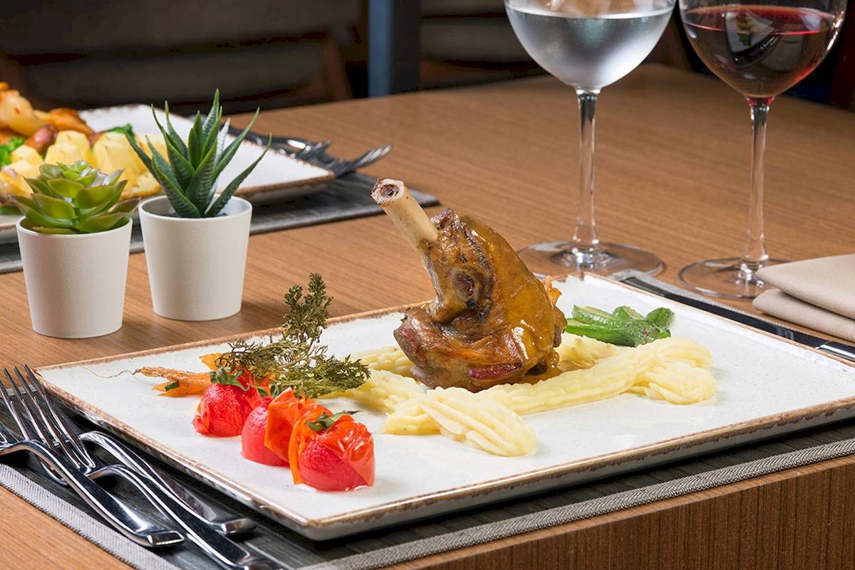 Essen am Tisch im Novum Garden Side Hotel mit Lammbraten, Gemüse und Wein