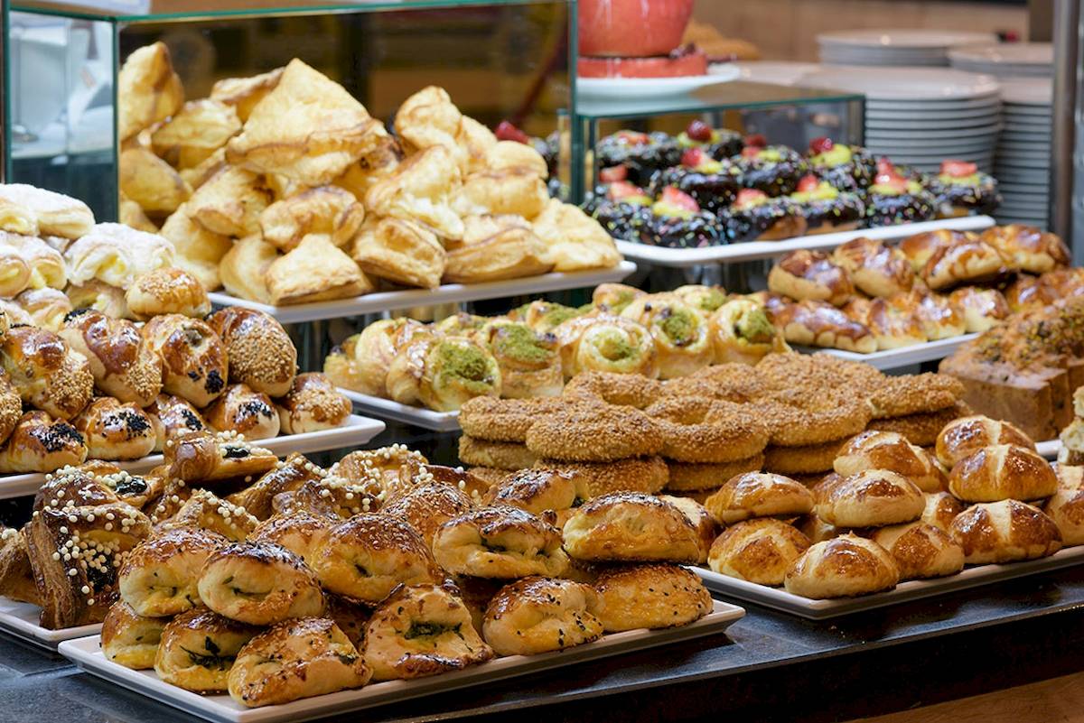 Ein Buffet mit einer Vielzahl von Gebäcksorten und Broten, darunter Croissants, Bagels und Brötchen.