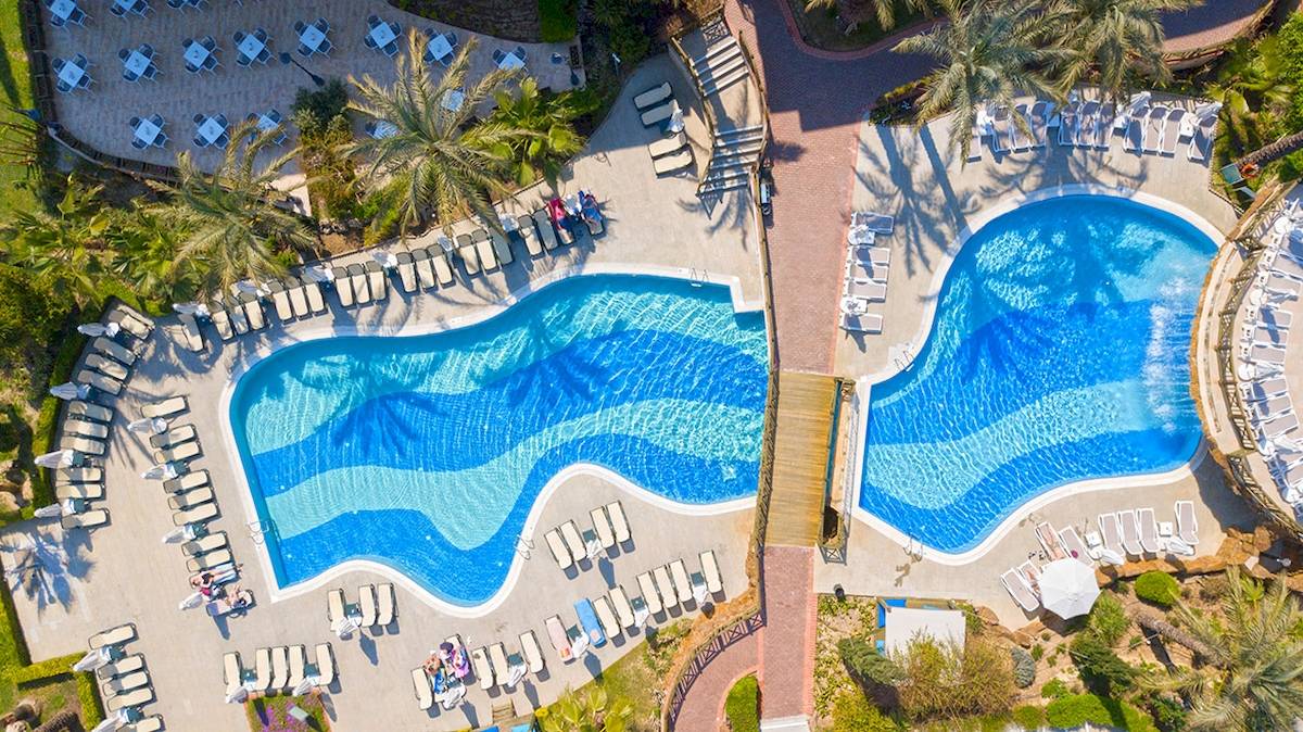 Luftaufnahme des Novum Garden Side Hotel Poolbereichs mit zwei Schwimmbecken und Sonnenliegen.