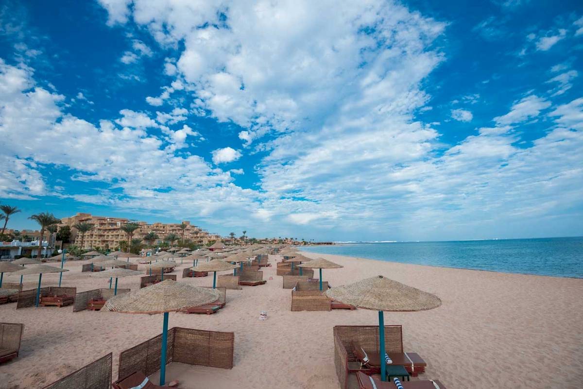 Sandstrand mit Sonnenhutten im Shams Safaga Resort, Blick auf das Meer und die Hotelanlage.