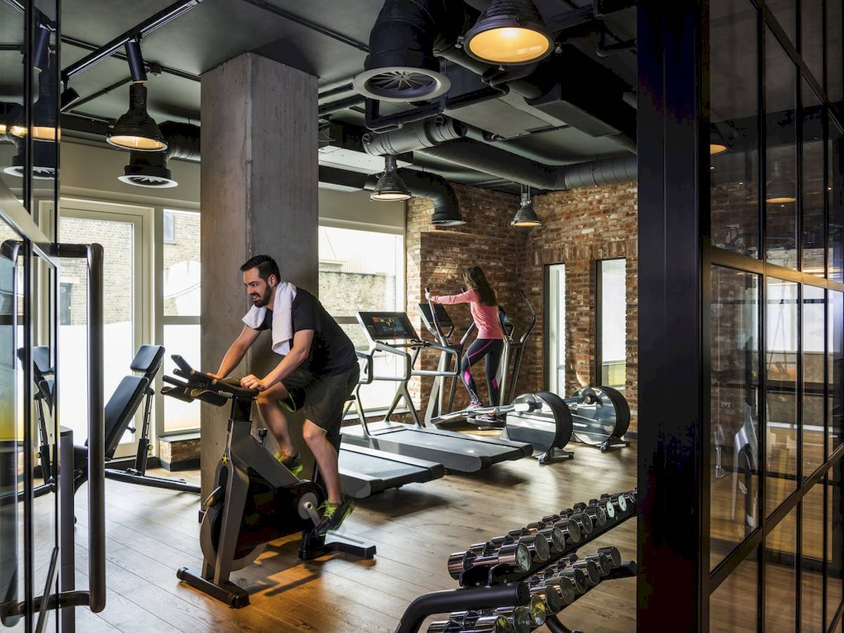 Fitnessstudio im Novotel London Canary Wharf mit Mann auf Fahrrad und Frau auf Laufband.