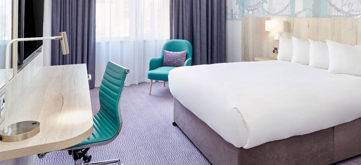 Leonardo Hotel London Croydon Zimmer mit Bett, Schreibtisch und Stühlen.
