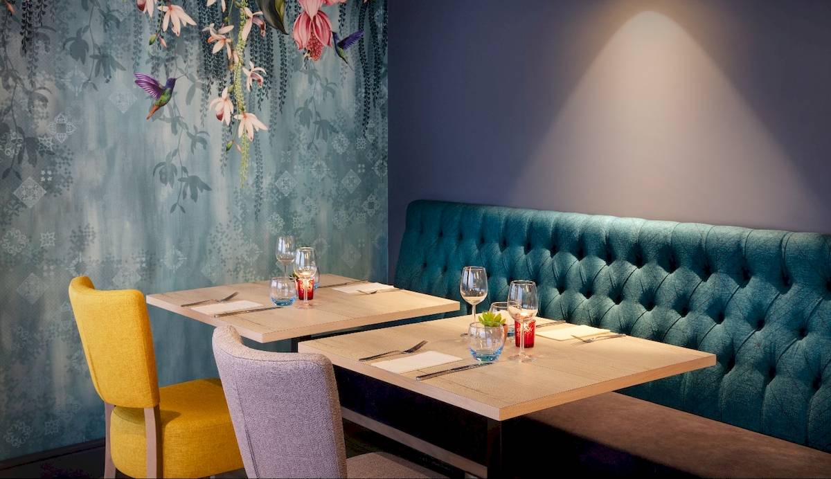 Restaurant des Leonardo Hotel London Croydon mit blauer Wand und bunten Stühlen.