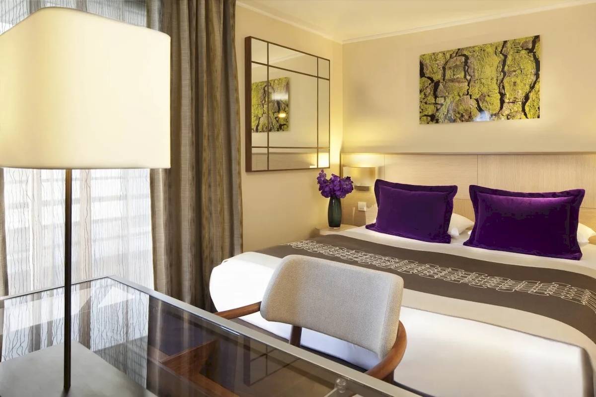 Luxus Hotel Schlafzimmer mit Bett, violetten Kissen und Blumenvase