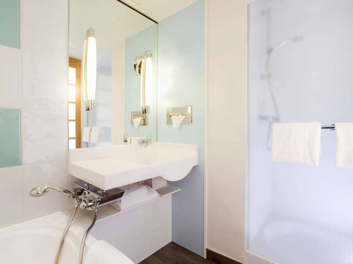 Badezimmer im Novotel Paris Tour Eiffel mit weißer Badewanne und Duschkabine.