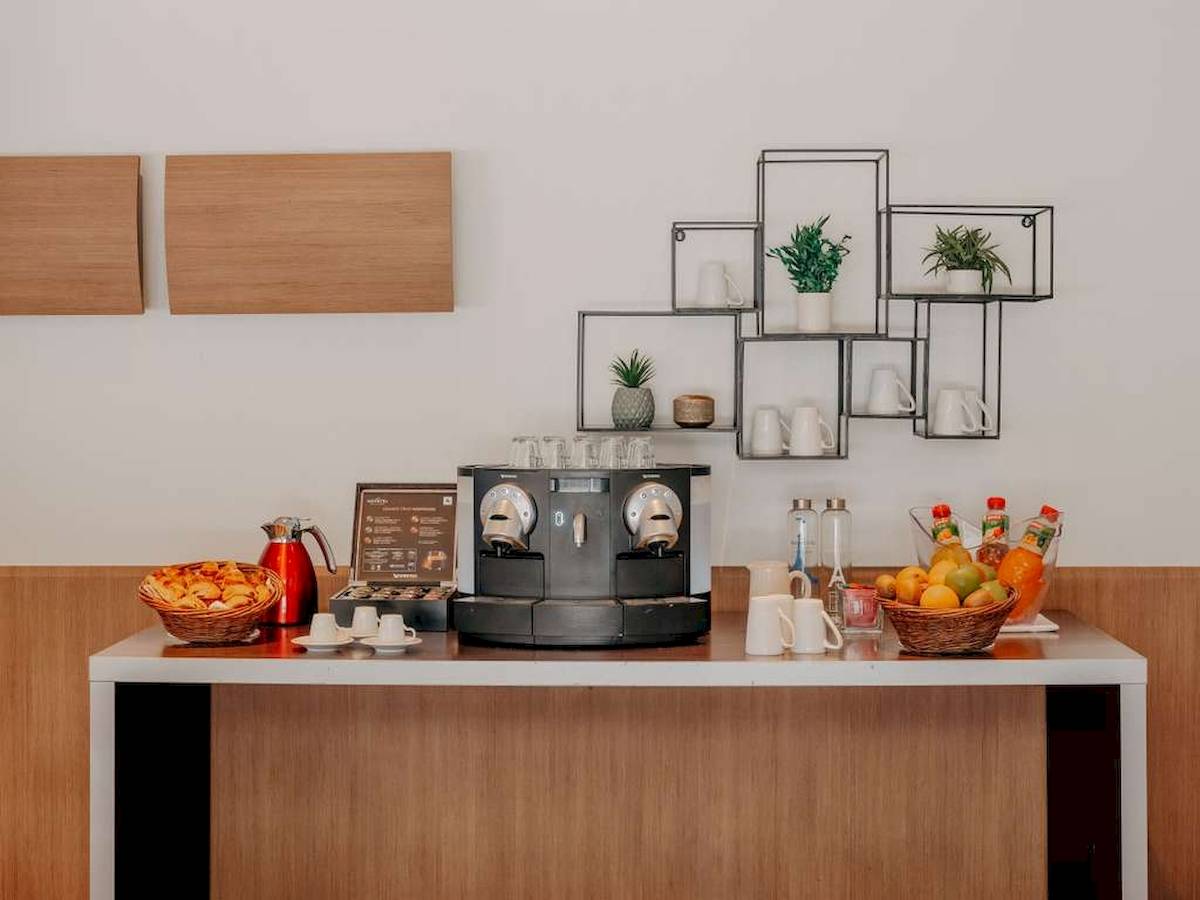 Frühstücksbuffet im Novotel Paris Tour Eiffel mit Kaffeemaschine, Obst und Getränken.