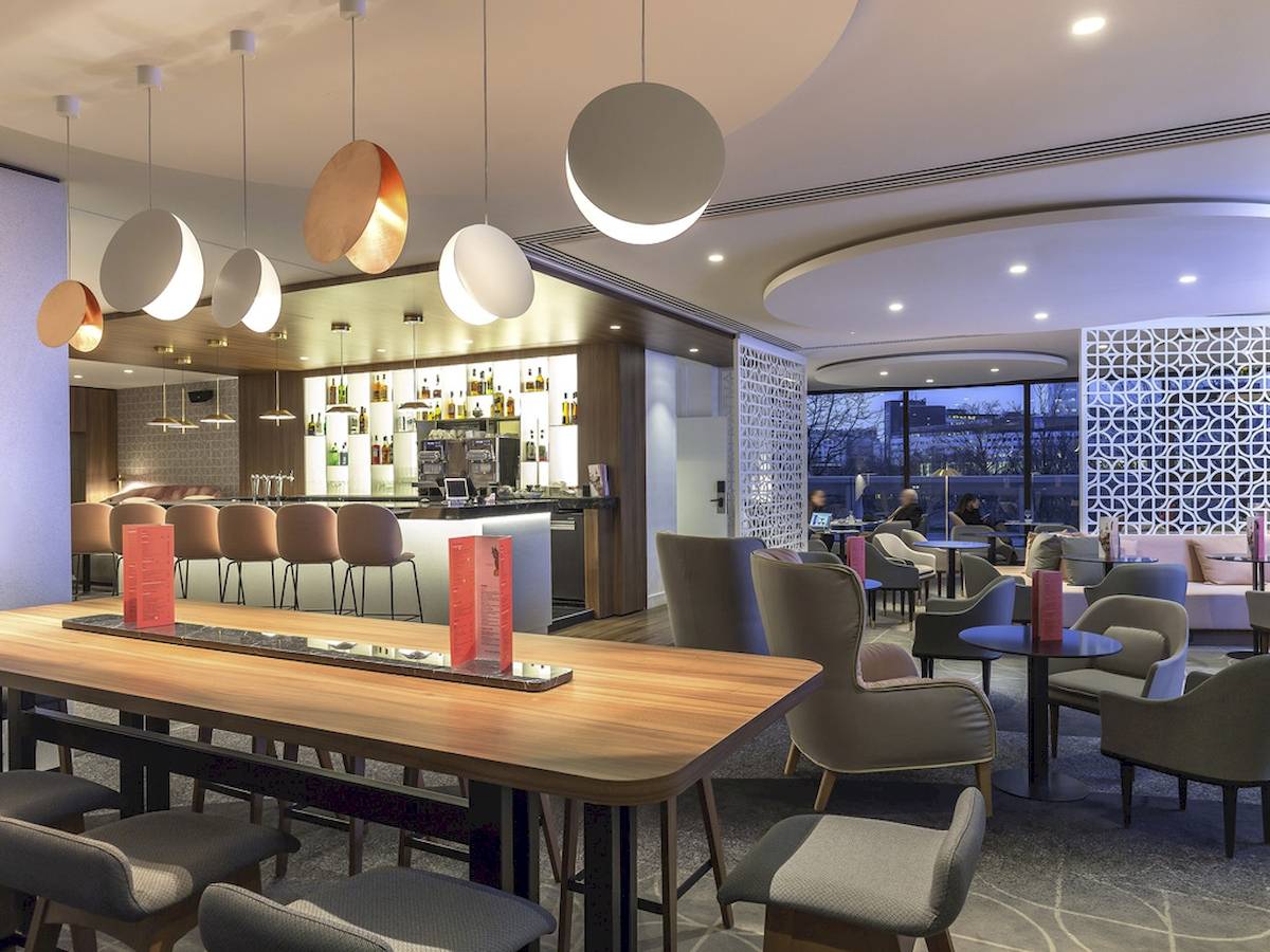 Loungebereich des Novotel Paris Tour Eiffel Hotels mit Bar, Tischen und Stühlen.