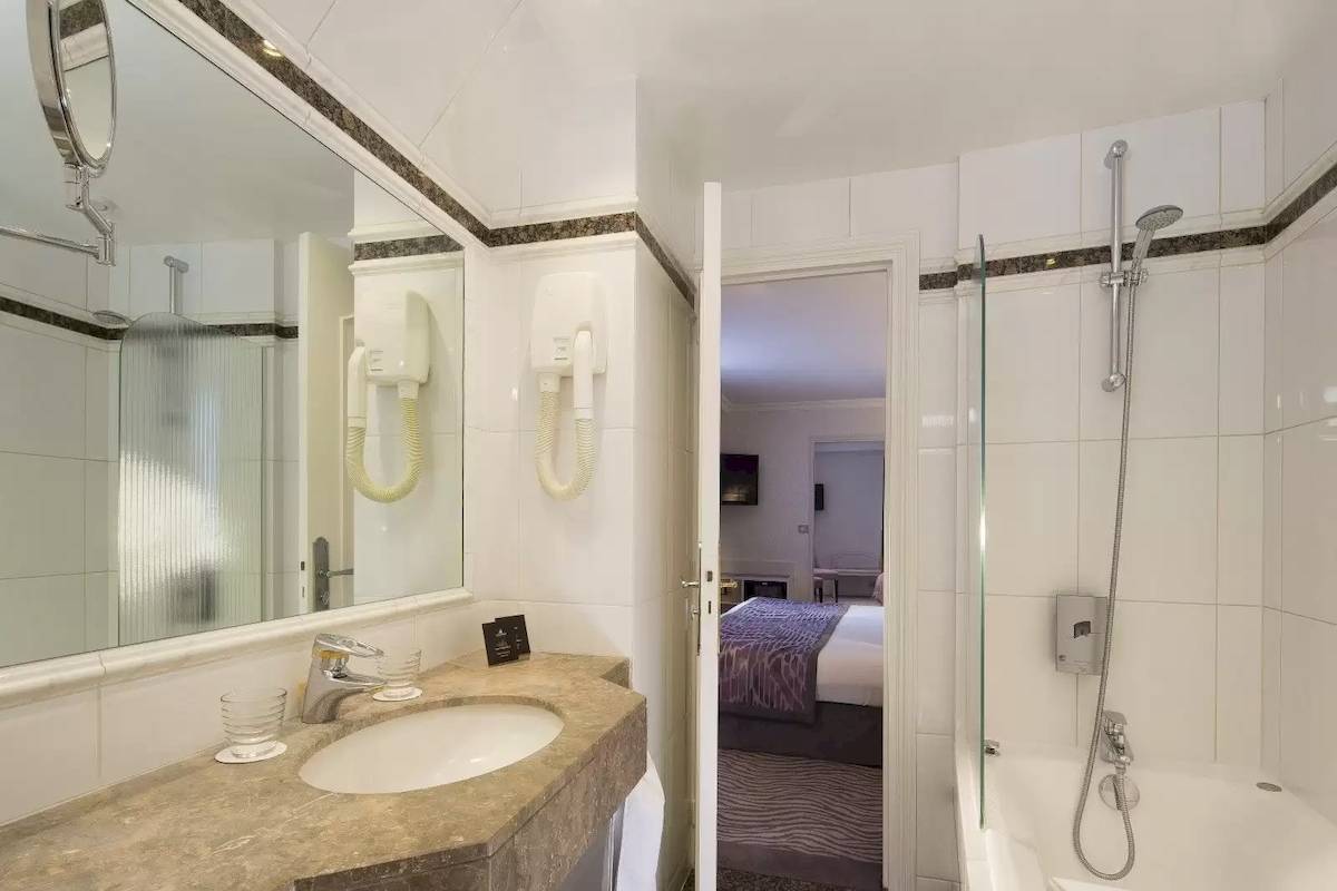 Badezimmer im Victor Hugo Paris Kléber Hotel mit Badewanne, Dusche und Waschbecken.