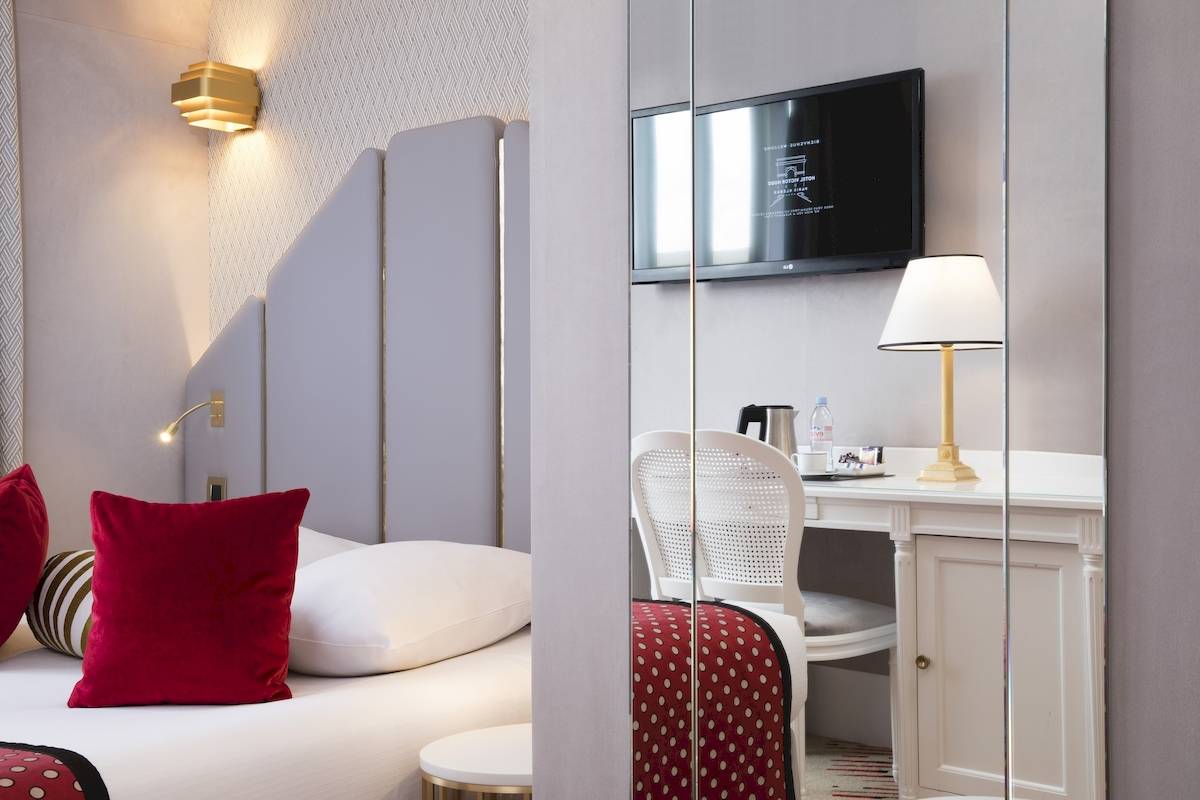 Innenansicht eines eleganten Hotelzimmers im Victor Hugo Paris Kléber mit einem Bett, einem Schreibtisch und einem Fernseher.