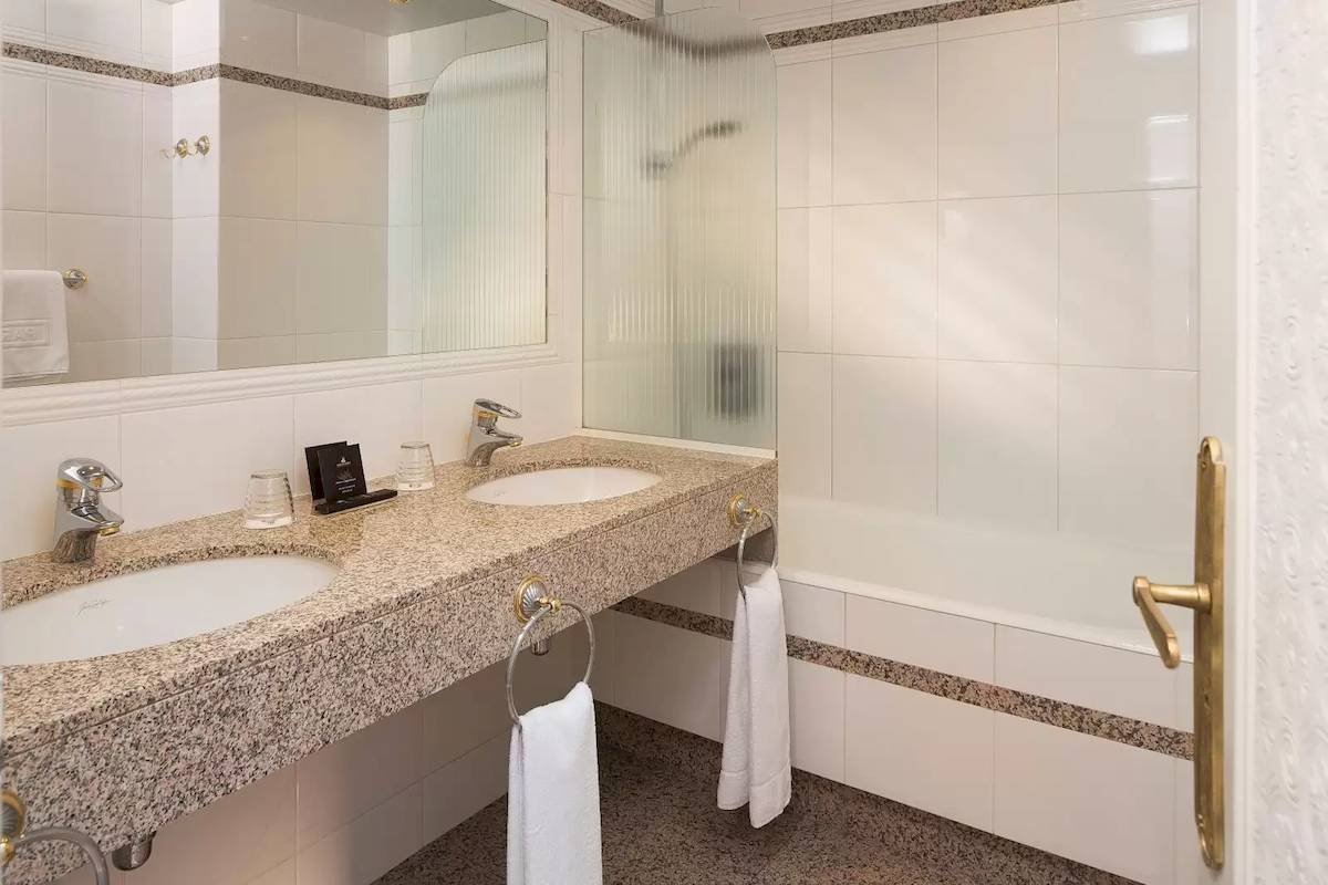 Badezimmer des Victor Hugo Paris Kléber Hotels mit zwei Waschbecken und Badewanne.