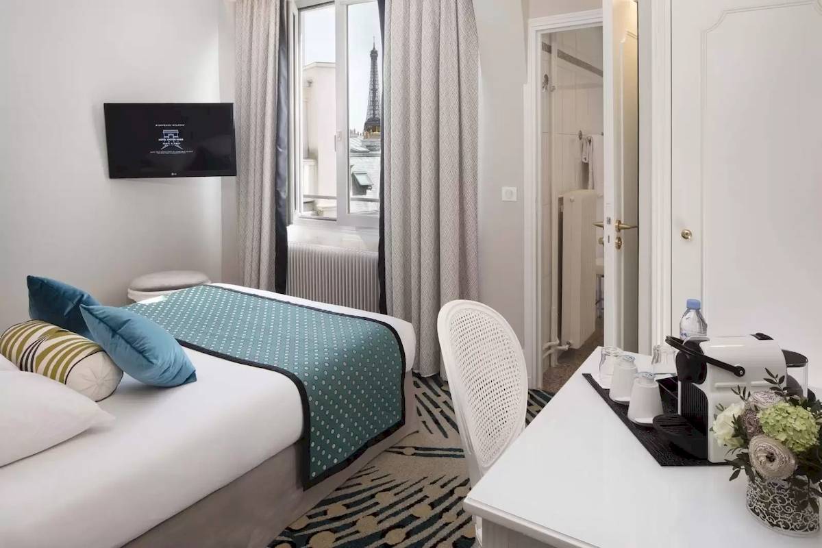 Innenansicht eines Zimmers im Hotel Victor Hugo Paris Kléber mit Bett, Schreibtisch und Blick auf die Eiffelturm.