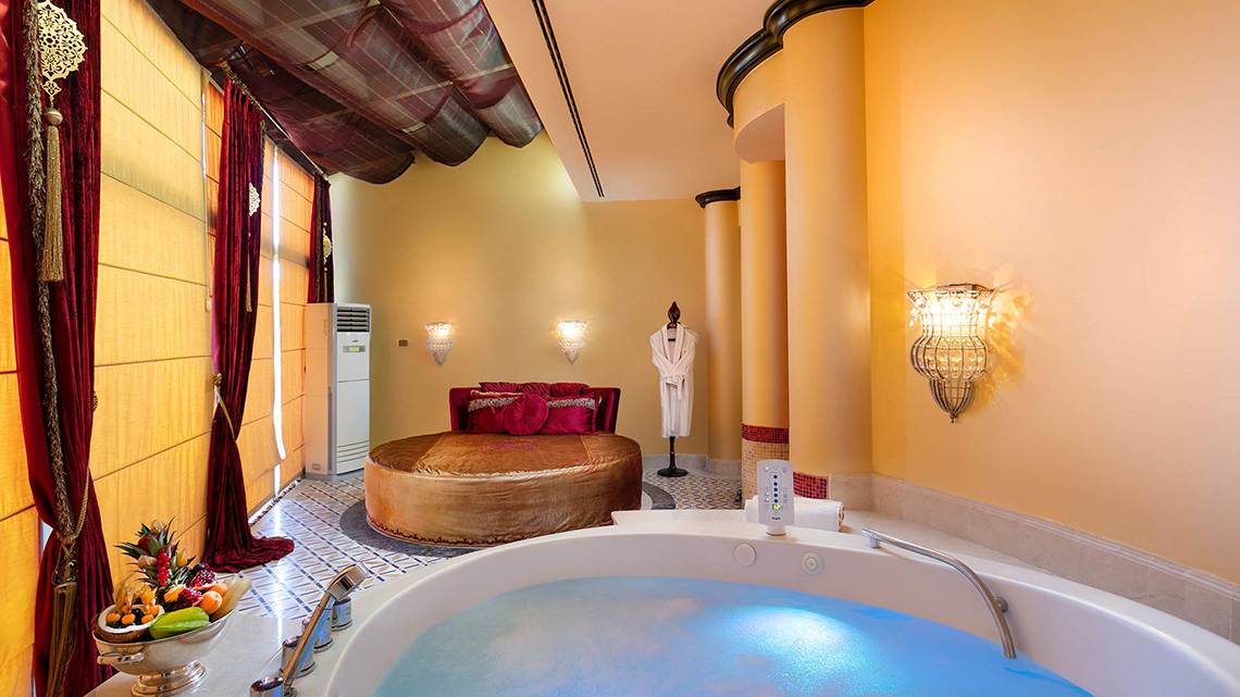 Suite Badezimmer im Titanic Mardan Palace mit Badewanne, Bett und Früchtekorb.