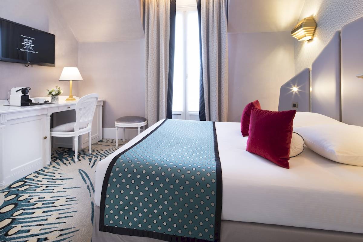 Ein geräumiges Hotelzimmer mit einem Bett, Schreibtisch, Stuhl und Fernseher.