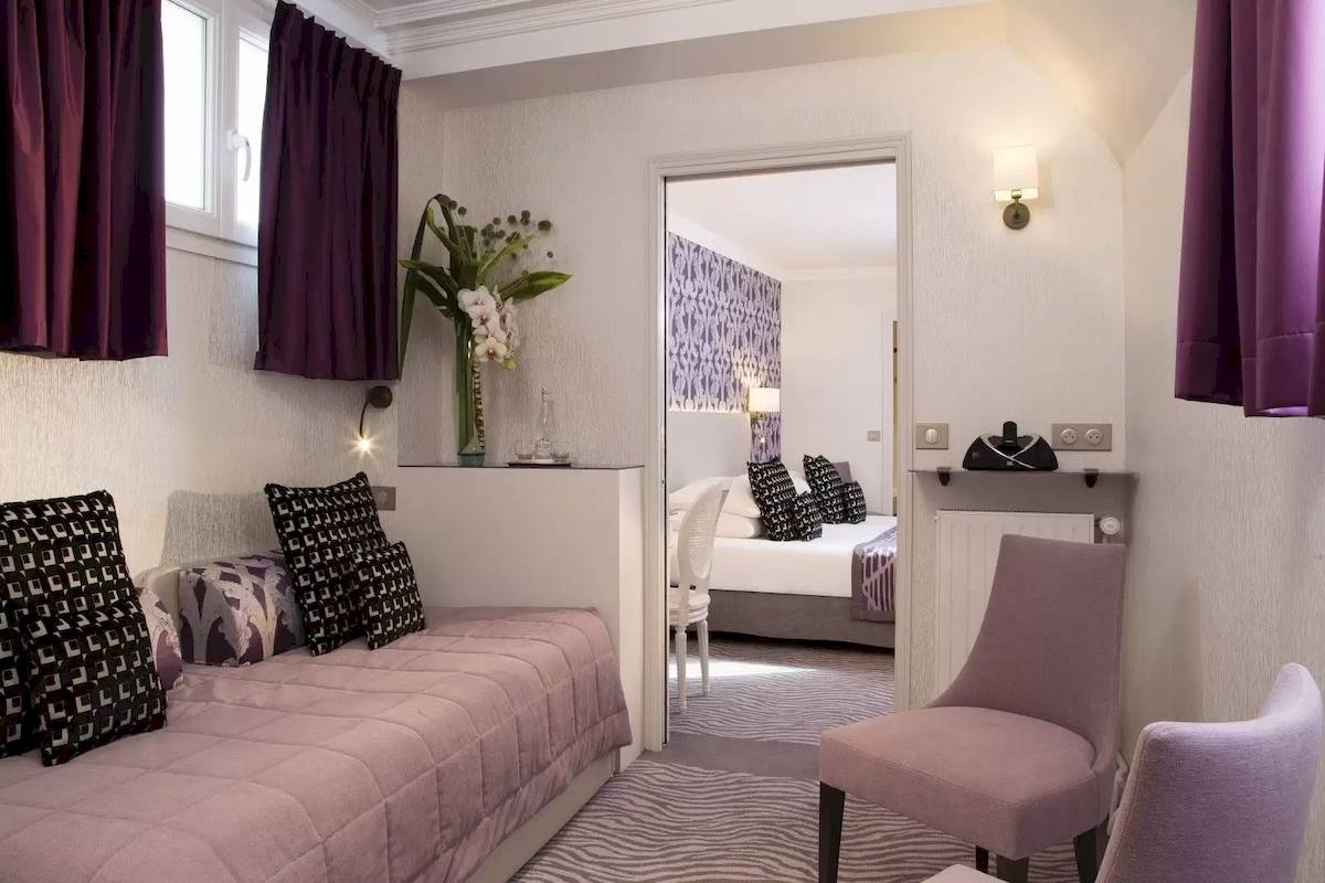 Zimmer im Victor Hugo Paris Kléber Hotel mit Schlafsofa, zwei Sesseln und Schlafzimmer im Hintergrund.
